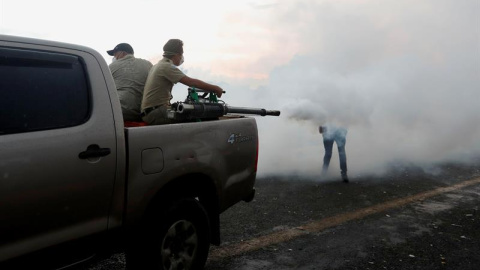 Empleados del ministerio de Salud fumigan contra mosquitos en el puente de la frontera entre Guatemala y México. EFE/ESTEBAN BIBA