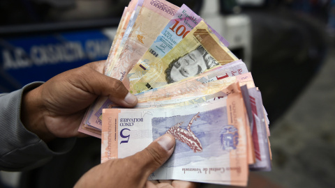 Un hombre cuenta bolívares en una calle de Caracas el 29 de enero de 2019 | AFP/Luis Robayo