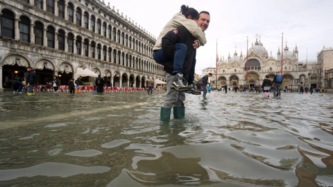 Un hombre carga a sus espaldas con su hija en la Plaza de San Marco de Venecia, inundada como consecuencia del temporal de lluvias. Andrea Merola/EFE