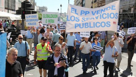 Varias personas sujetan una pancarta en la que se lee: 'El PP vende los servicios públicos' durante una marcha contra la reforma de la Ley de Transportes, a 1 de junio de 2022, en Madrid (España).