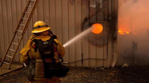 Un bombero apagando un fuego en el interior de una propiedad. EFE/ Peter Dasilva