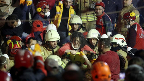 Varios efectivos de los equipos de rescate transportan a una mujer herida, este miércoles en Estambul tras el derrumbe de una edificio de viviendas.-EFE