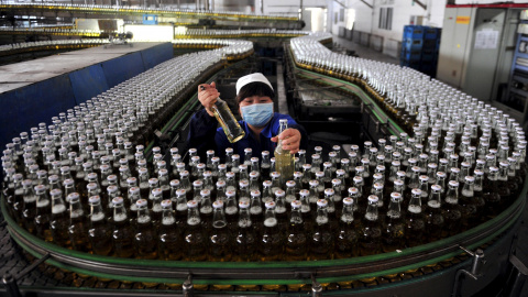 Una mujer recoge botellas de cerveza en una cadena de montaje dentro de una fábrica en Shenyang. REUTERS