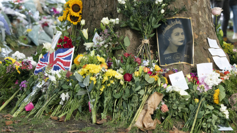 La imagen de la reina yace junto a flores y banderas en su memoria.