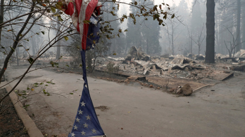 Una bandera estadounidense hecha jirones cuelga cerca de una de las casas destruidas en Camp Fire, Paradise.- REUTERS