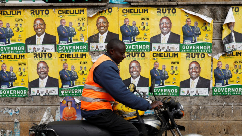 Un motorista pasa junta a una pared empapelada con los carteles electorales del actual vicepresidente de Kenia, y aspirante a la presencia, William Ruto, en las elecciones generales, en la localidad keniata de Eldoret. REUTERS/Baz Ratner