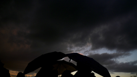 Un grupo de personas se refugia de la lluvia con sus paraguas en el parque madrileño del Templo de Debod. REUTERS/Sergio Perez