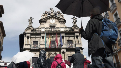 Un grupo de turistas se protegen con sus paraguas de la lluvia junto al Ayuntamiento de Pamplona, uno de los lugares preferidos para la Semana Santa. EFE