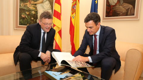 El presidente del Gobierno, Pedro Sánchez, hojea un libro en presencia del presidente de la Generalitat Valenciana, Ximo Puig.