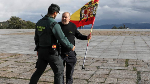 Un hombre con una bandera fascista forcejea con un Guardia Civil. (SUSANA VERA | REUTERS)