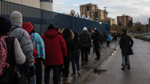 Un agente de policía reparte los turnos de los 80 solicitantes de asilo que serán atendidos en la comisaría de Aluche.- JAIRO VARGAS