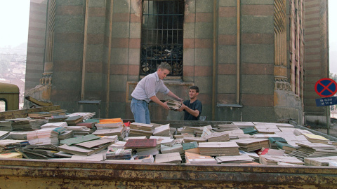 Residentes de Sarajevo intentan salvar algunos libros del incendio provocado por un bombardeo serbio en la Biblioteca Nacional de Bosnia, el 29 de agosto de 1992.- AFP