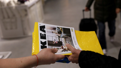 Un trabajador de Ikea entrega un catálogo a un cliente a la entrada de una de sus tiendas en Madrid. REUTERS/Susana Vera