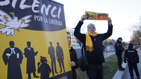 Una persona con lazo y bufanda amarilla y con un cartel que induce a la justicia a colabora con el independentismo en una concentración frente al Tribunal Supremo