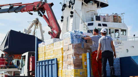 Operarios de Open Arms supervisan la carga de ayuda humanitaria al buque tras recibir la autorización para zarpar del puerto de Barcelona./ Alejandro García (EFE)