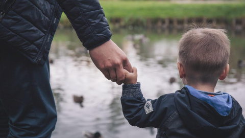 Un niño camina de la mano de una persona adulta, en una imagen de archivo