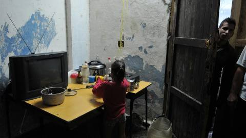 Fotografía de archivo fechada el 10 de septiembre de 2008 que muestra a una niña mientras lava platos en una improvisada cocina en el poblado José Martí, municipio de San Cristóbal, provincia de Pinar del Río