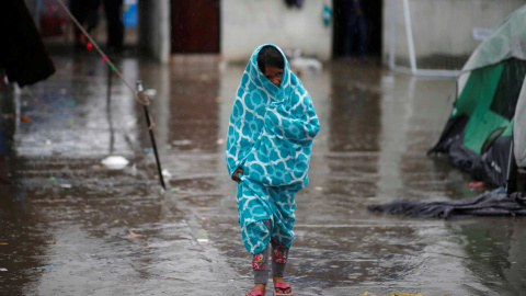 Una niña centroamericana que viaja en una caravana de migrantes, envuelta en una toalla para protegerse de la lluvia en un refugio de Tijuana. / REUTERS - MOHAMMED SALEM