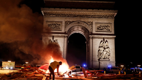 Un manifestantes de los llamados "chalecos amarillos" prende fuego a una barrica frente al Arco del Triunfo de París en la manifestación contra el alza de precio de los carburantes.- REUTERS/Benoit Tessier