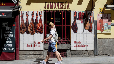 Una pareja de turistas pasa por delante de una jamonería en el centro de Madrid. REUTERS/Paul Hanna