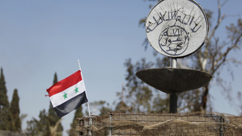 Una foto de archivo de una bandera nacional siria ondeando junto al eslogan del Estado Islámico en una rotonda donde las ejecuciones fueron llevadas a cabo por militantes de ISIS en la ciudad de Palmira./REUTERS