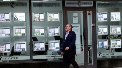 Un hombre pasa por delante de una oficina de una inmobiliaria en Barcelona. REUTERS/Albert Gea