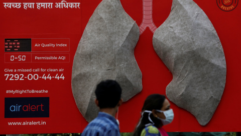 Unas personas pasan junto a un aviso sobre los efectos de la contaminación colocado en el exterior de un hospital en Nueva Delhi. REUTERS/Anushree Fadnavis