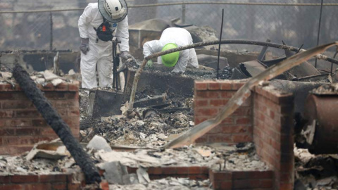 Miembros de un equipo de rescate buscan restos humanos en una de las miles de casas quemadas en California. (TERRAY SILVESTER)