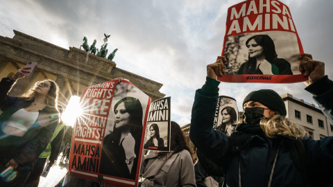 28/09/2022-Manifestantes sostienen pancartas con una imagen de Mahsa Amini durante una concentración en reacción a su muerte, frente a la Puerta de Brandenburgo en Berlín, Alemania, 28 de septiembre de 2022.