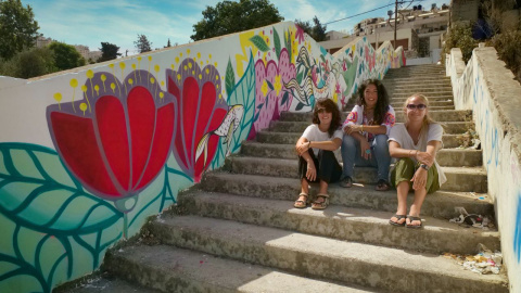 Las muralistas Irene Bofill, Iris Serrano y Julieta Xlf, junto a uno de su murales.