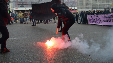 Una mujer recoge una de las bengalas que han encendido durante la marcha en un punto de la manifestación - Arancha Ríos