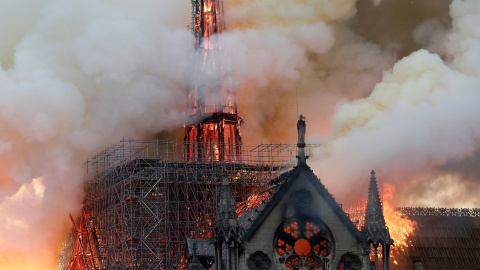 El humo ondea cerca de los andamios cuando el fuego envuelve la aguja de la catedral de Notre Dame. / Reuters