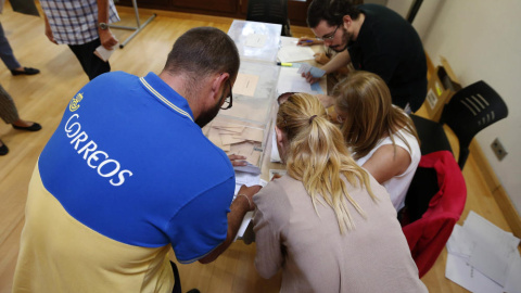 Un funcionario de Correos entrega en una mesa electoral los votos por correo. EFE