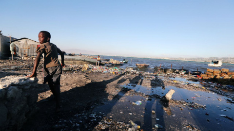 Un niño camina a lo largo de una costa contaminada con basura en Puerto Príncipe, Haití. / Reuters