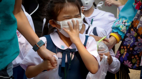 Una niña tailandesa aprieta la mascarilla que utiliza para protegerse de la contaminación en Bangkok. / EFE