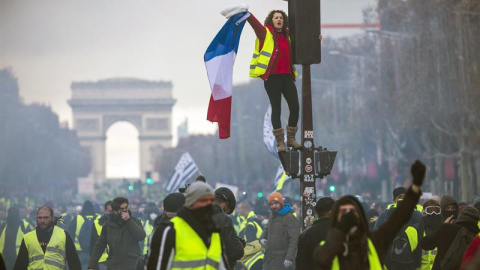 Una mujer grita consignas subida a un semáforo durante una protesta en los Campos Elíseos en París (Francia) hoy, 24 de noviembre de 2018. El ministro francés del Interior, Christophe Castaner, culpó hoy a la ultraderecha y a su líder, Marine Le Pen