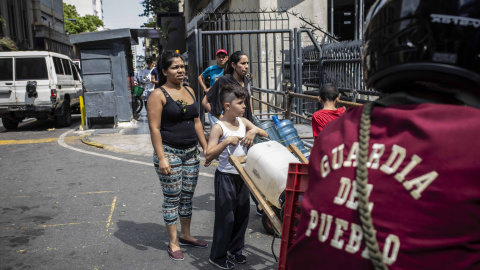 Una familia se topa con una calle cortada por la marcha cuando va a recoger agua en Caracas.