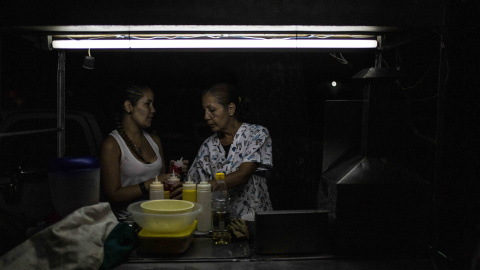 Yugli y su hija Laura atienden su puesto de parrilla en una calle del barrio 23 de Enero de Caracas.- JAIRO VARGAS