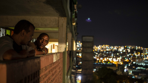 Dos vecinos de uno de los bloques del barrio 23 de Enero de Caracas conversan durante la noche.- JAIRO VARGAS