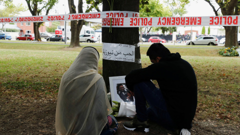 Una mujer y un hombre sentados mirando una imagen de una de las víctimas del tiroteo en Christchurch, Nueva Zelanda. REUTERS / JORGE SILVA