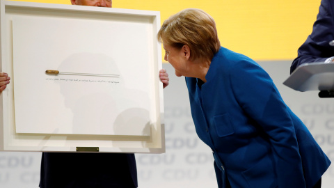 La canciller alemana, Angela Merkel, recibe la batuta del director de orquesta Kent Nagano como regalo de despedida durante el congreso de la CDU, en Hamburgo, en el que se decide su sucesor o sucesora al frente del partido. REUTERS / Fabrizio Bensch