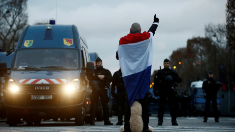 Un hombre arropado con la bandera de Francia mira de frente a la Policía. REUTERS/Christian Hartmann