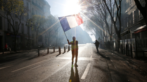 Uno de los manifestantes de los chalecos amarillos porta una bandera de Francia en las calles de Marsella.- REUTERS/Jean-Paul Pelissier