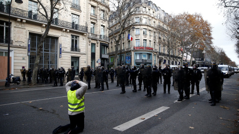 Un manifestante se arrodilla y posa sus manos sobre la cabeza mientras mira de frente a los policías antidisturbios que se protegen con sus escudos.- REUTERS/Stephane Mahe