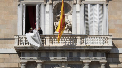 Operarios, terminando de retirar el cartel que colgaba de la fachada del Palau de la Generalitat. - EFE