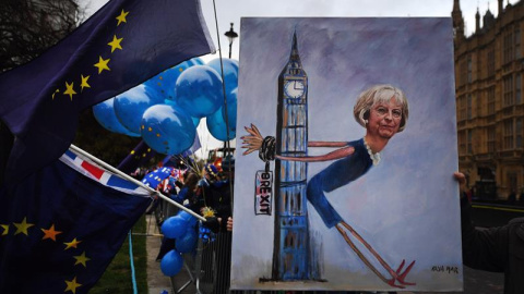 La artista Kaya Mar muestra un cuadro de la primer ministra británica Theresa May durante una manifestación en contra del brexit a las afueras del Parlamento en Londres. - EFE