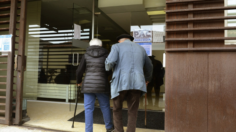 Dos personas mayores entran por la puerta de la residencia.