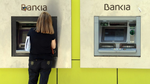 Una mujer opera en un cajero automático en una sucursal de Bankia en Madrid. AFP