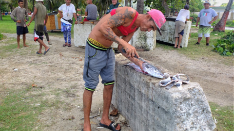 Fotografía de un pescador cubano manipulando uno de sus pescados.