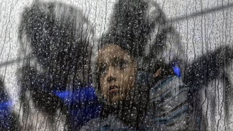 Una niña centroamericana que viaja en una caravana de migrantes, toma un autobús fuera de un refugio temporal en el este de Tijuana, México, el 6 de diciembre de 2018 | Guillermo Arias/AFP